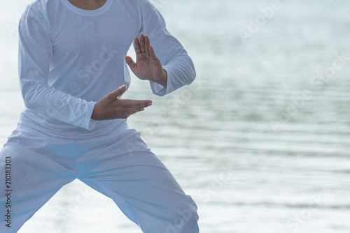 Young man practicing traditional Tai Chi Chuan, Tai Ji and Qi gong in the park for healthy, traditional chinese martial arts concept.