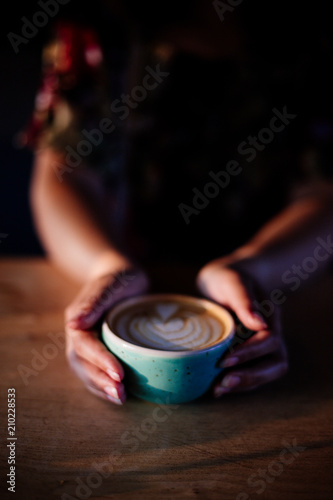 Cup of cappuccino in hands.