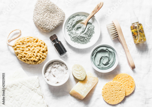 Spa accessories - nut scrub, sponge, facial brush, natural soap, clay face mask, pumice stone, essential oil on a light background, top view. Healthy lifestyle concept. Beauty, skin care. flat lay