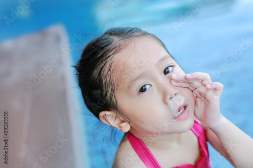 Mucus flowing from nose of little asian child girl while swimming at pool.