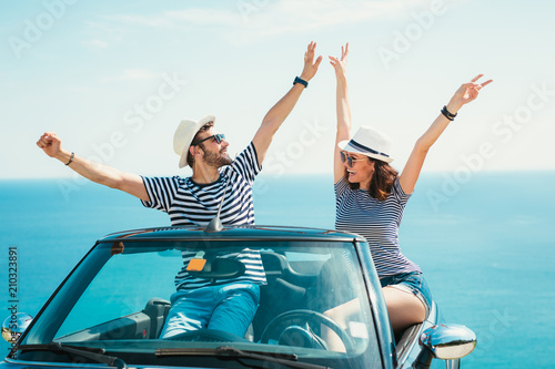 Young attractive couple posing in a convertible car, by the sea