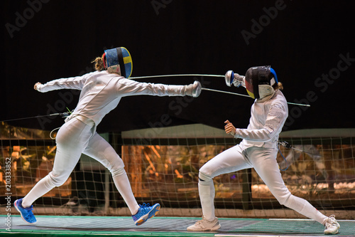 Two woman fencing athletes fight