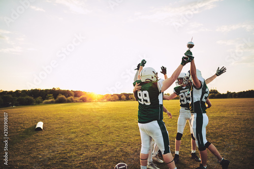 Excited football players standing outside celebrating with a cha