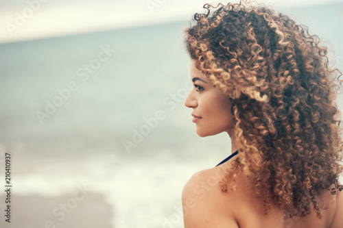 Lovely woman portrait on the beach looking aside and smiling