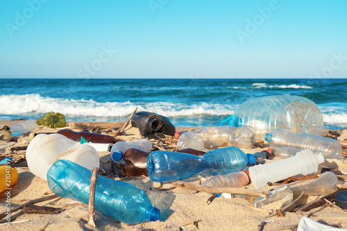 Spilled garbage on the beach of the big city. Empty used dirty plastic bottles. Dirty sea sandy shore the Black Sea. Environmental pollution. Ecological problem. Bokeh moving waves in the background 