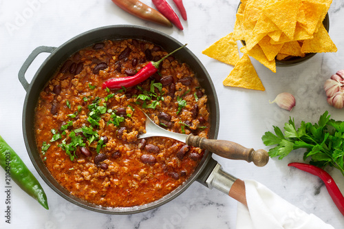 Mexican and American food Chili con carne served with nachos, pepper and herbs.