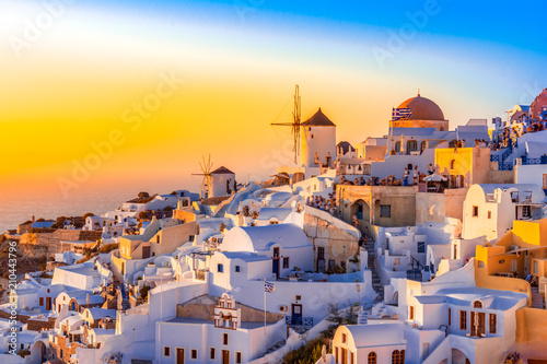 Sunset in Oia town, Santorini island, Greece. Traditional and famous white houses and churches with blue domes over the Caldera, Aegean sea.