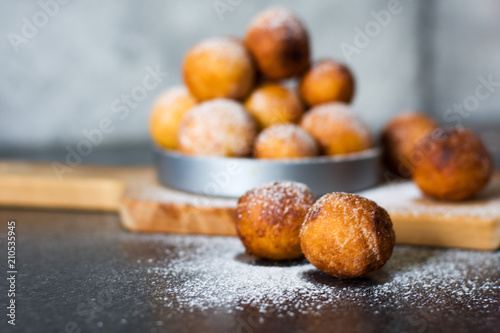 Donuts close-up. Italian fritters - traditional dish on a gray background on a wooden board.