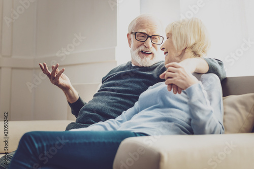 Aged couple. Joyful aged woman looking at her beloved man while listening to his jokes