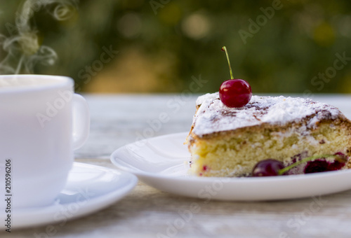 Вкусный кусок вишневого пирога на белой тарелке и белая чашка горячего чая с лимоном. Крупный план. Мокап.