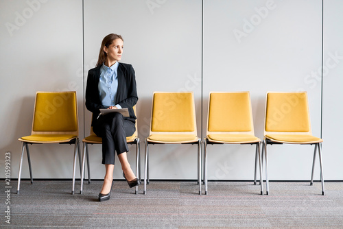 Young woman sitting in lobby with resume in hands and waiting for job interview