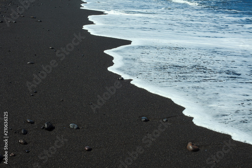 Black sand beach with white ocean foam
