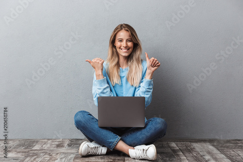 Happy young blonde girl using laptop computer