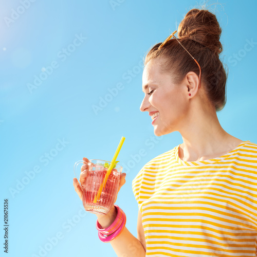 smiling woman against blue sky drinking refreshing cocktail