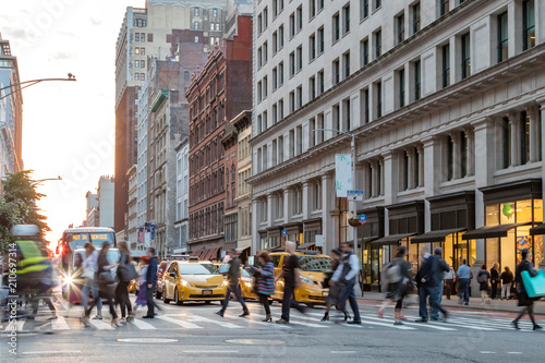 Fast paced street scene with people walking across a busy intersection on Broadway in Manhattan New York City