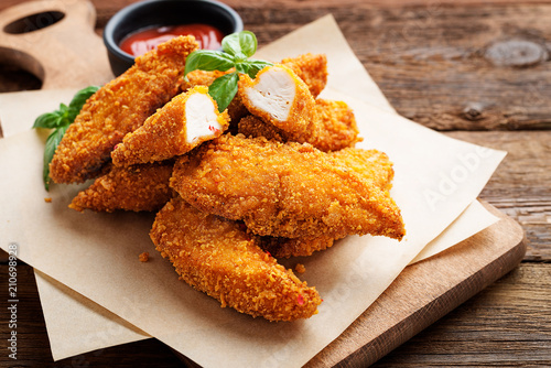 Delicious crispy fried breaded chicken breast strips with ketchup.