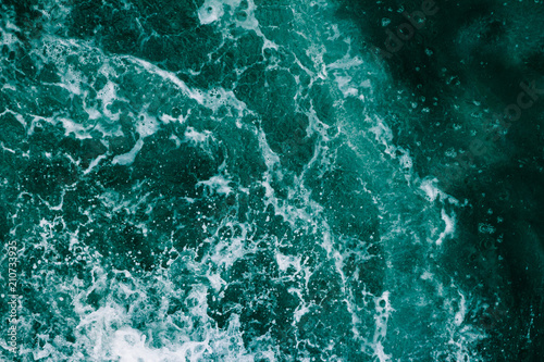 Surface of the sea with waves, splash, foam and bubbles at high tide and surf, green abstract background