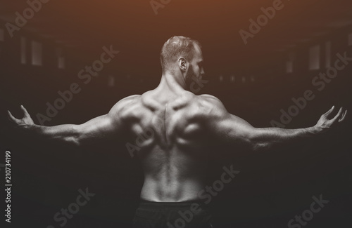 Silhouette of a slender bodybuilder doing sports in the gym.