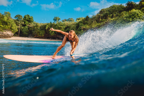 Beautiful surfer girl on surfboard. Woman in ocean during surfing in Bali