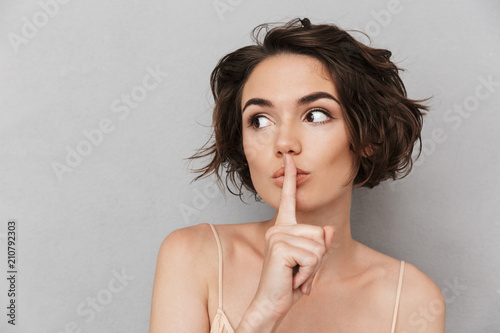 Close up of a worried young woman showing silence gesture