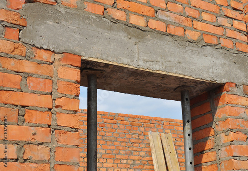 Concrete door lintel installation with metal holders. Door concrete lintel on brick unfinished house construction.