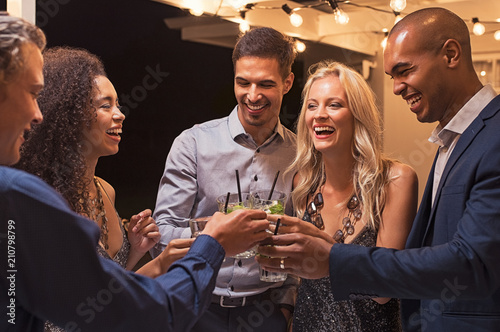 Friends toasting cocktail at night party