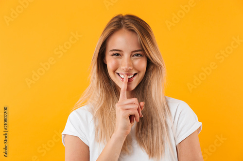 Portrait of a smiling young blonde girl showing silence