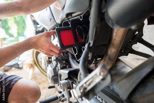Man hands changing the air filter on his motorbike, doing maintenance