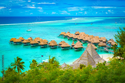 Aerial view of overwater bungalow luxury resort in turquoise lagoon water of Moorea, French Polynesia.