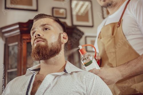 Man with beard uses the services of a barber. Photo in vintage style