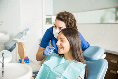 Dentist Showing Braces To Teenage Girl In Mirror At Clinic