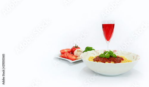 Makaron spagetti z sosem neapolitańskim i lampką czerwonego wina na białym tle.