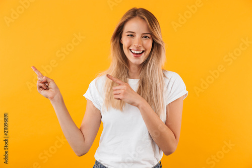 Portrait of a joyful young blonde girl pointing