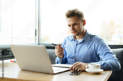 Young man drawing template for the web site associated with digital marketing, current trends and tendencies of UX / UI design. Businessman who rules his company remotely, like a freelancer