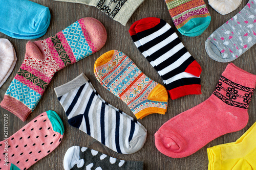 Multicolored knitted socks. Many socks with a different pattern on a wooden background. Warm clothes for autumn and winter. View from above.