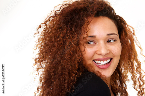 Close up beautiful young woman with curly hair laughing against isolated white background