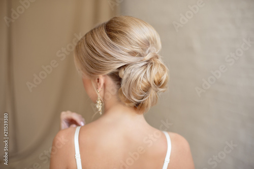 Rear view of female hairstyle middle bun with blond hair.