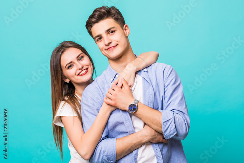 Young hug couple smiling on a blue background