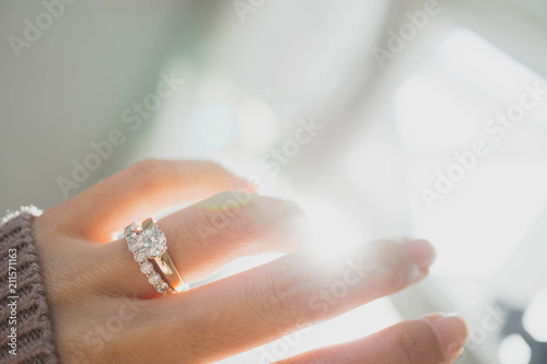 Close up of elegant diamond ring on woman finger with dark pink sweater winter clothe and sunlight tone. love and wedding concept.soft and selective focus.