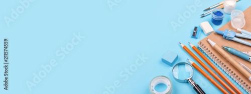 School stationary on blue background. Notebook, pens, pencils and other tools. Banner for website.