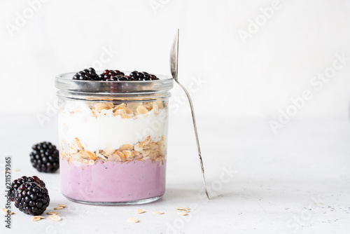 Yogurt parfait with blackberries and granola in a jar. Healthy breakfast, overnight oats or snack. Copy space for text