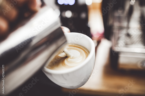 Coffee latte art, barista pouring milk into cup