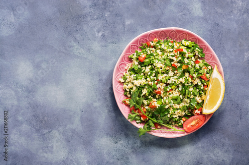 Tabbouleh salad, plate, rustic blue background.Traditional Lebanese dish. Middle Eastern diet food. Top view, copy space.