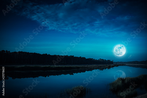 Night sky and bright full moon at riverside. Serenity nature background.