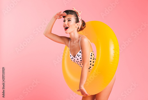 Gorgeous young pin-up woman in swimwear with inflatable ring. Looking aside.