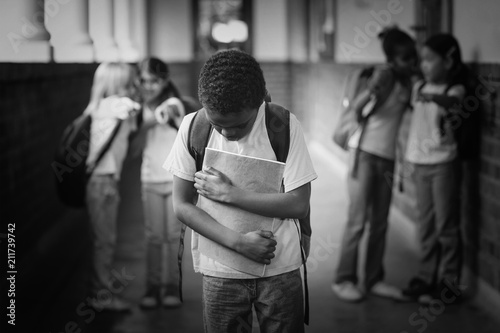 Sad pupil being bullied by classmates at corridor