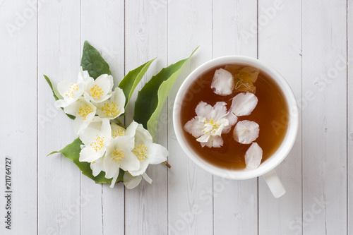 Mug of herbal tea with petals of Jasmine flowers on a light background