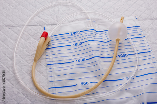 Nurse inflates urinary catheter bulb with leg drainage bag on sterile field.