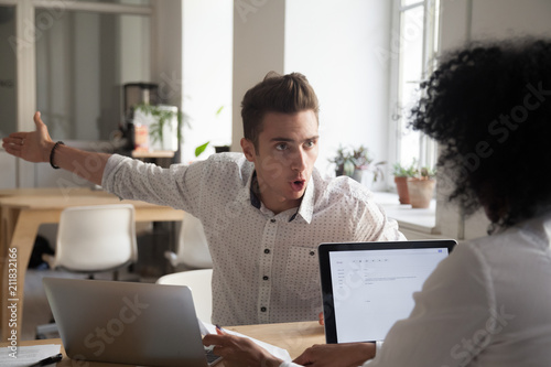 Mad male worker yelling at female colleague asking her to leave office, multiracial coworkers disputing during business negotiations, employees cannot reach agreement, blaming for mistake or crisis