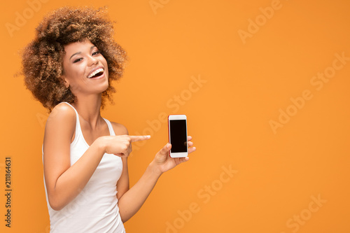 Smiling afro girl with blank screen mobile phone.